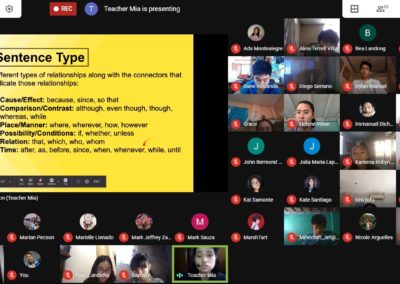 A teacher conducting an online review about Sentence Type. The teacher is engaged in a lecture while sharing slides . Some Students' faces can be seen in smaller video thumbnails, actively listening and participating.